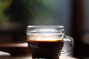 A clear glass mug with a handle, containing a dark liquid, likely coffee, with condensation on the outside. - Berbeda Place (Palo Alto)