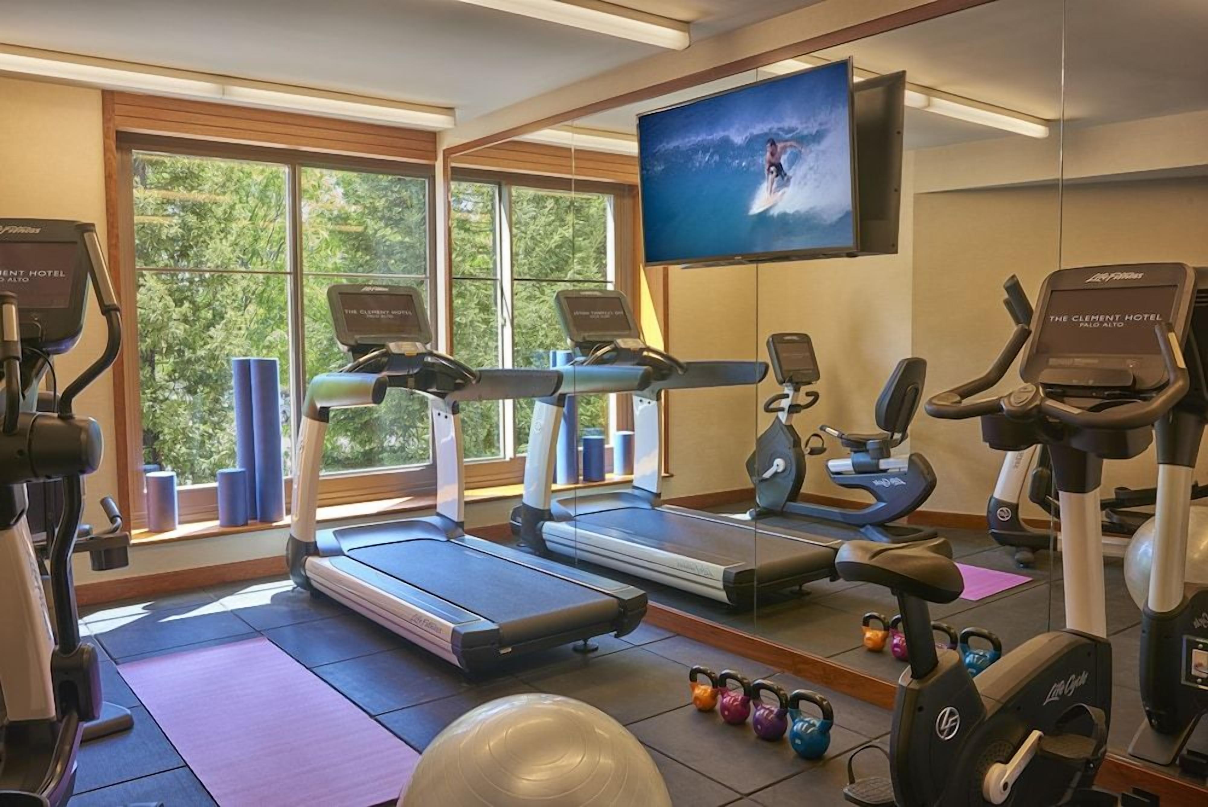 A gym with treadmills, elliptical machines, and kettlebells.