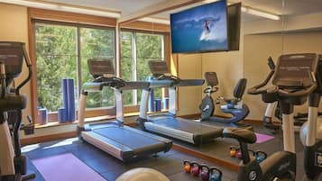 A gym with treadmills, elliptical machines, and kettlebells.
