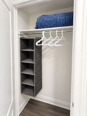 A closet with a hanging organizer and a blue blanket on top.