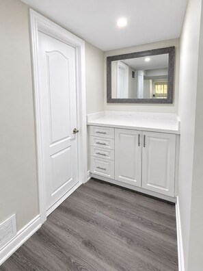 Un baño con tocador blanco, un espejo y una puerta.