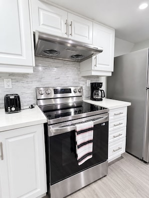 A modern kitchen with white cabinetry, a stainless steel range, and a built-in oven.
