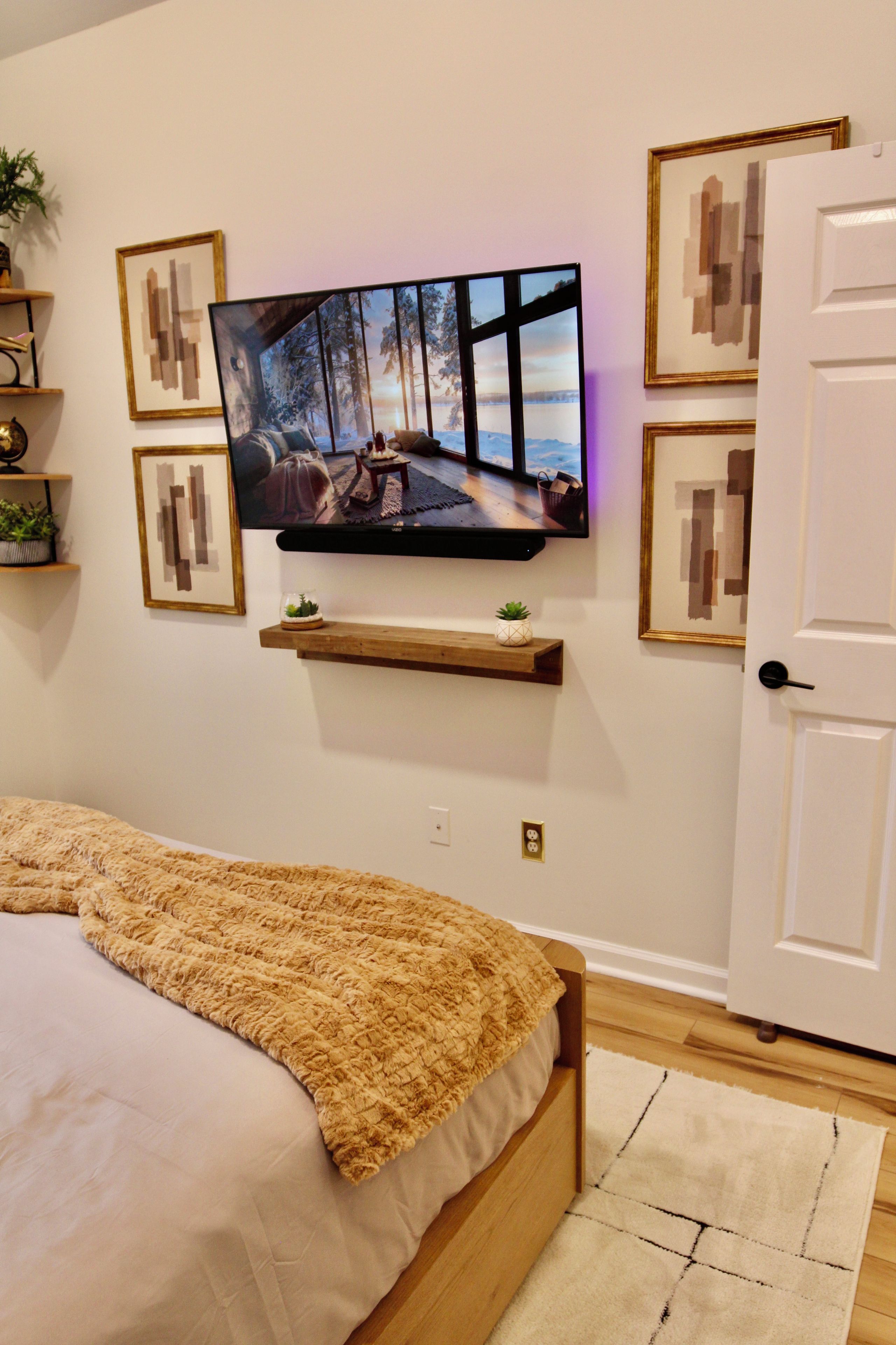 A bedroom with a bed, a television mounted on the wall, and a door.