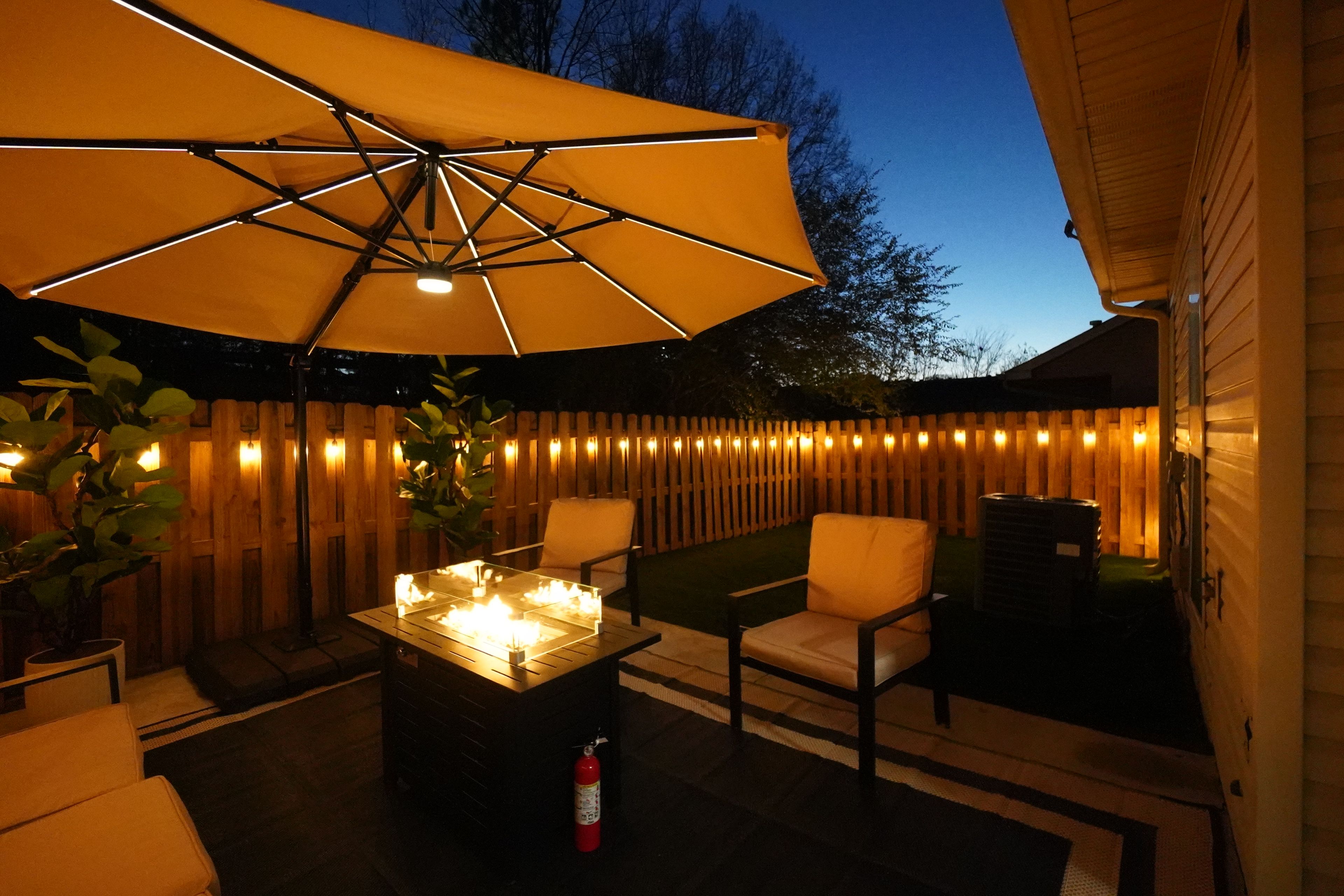 Un patio al aire libre con mesa, sillas y un paraguas grande.