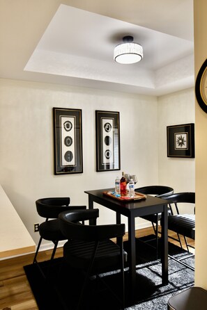 Zona pranzo con tavolo, sedie, un quadro incorniciato appeso al muro e una lampada a sospensione al soffitto.