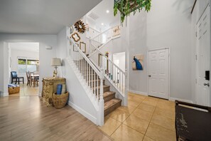 A spacious living area with a staircase, a dining table, and a decorative wall. - Saltwater pool + outdoor movies (Indio)
