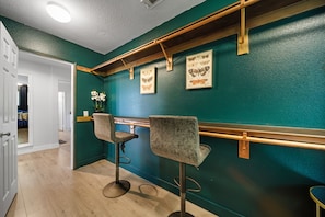 A bar area with teal walls, wooden bar counter, and two bar stools. - Saltwater pool + outdoor movies (Indio)
