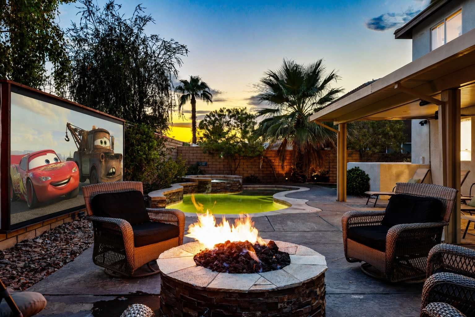 A backyard with a fire pit, outdoor seating, a swimming pool, and a mural of animated characters.