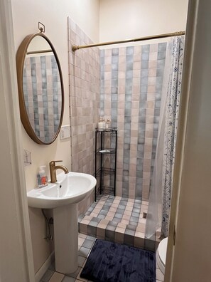 Une salle de bain avec un lavabo, un miroir, une douche et des murs carrelés.