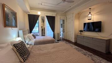 A bedroom with two beds, a ceiling fan, a TV, and a dresser.