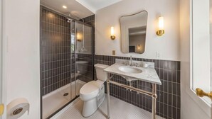 Un baño moderno con ducha envuelta en vidrio, inodoro y tocador con lavamanos.
