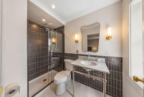 A modern bathroom with a glass-enclosed shower, a toilet, and a vanity with a sink. - The Pines Inn Lake Placid (Lake Placid)