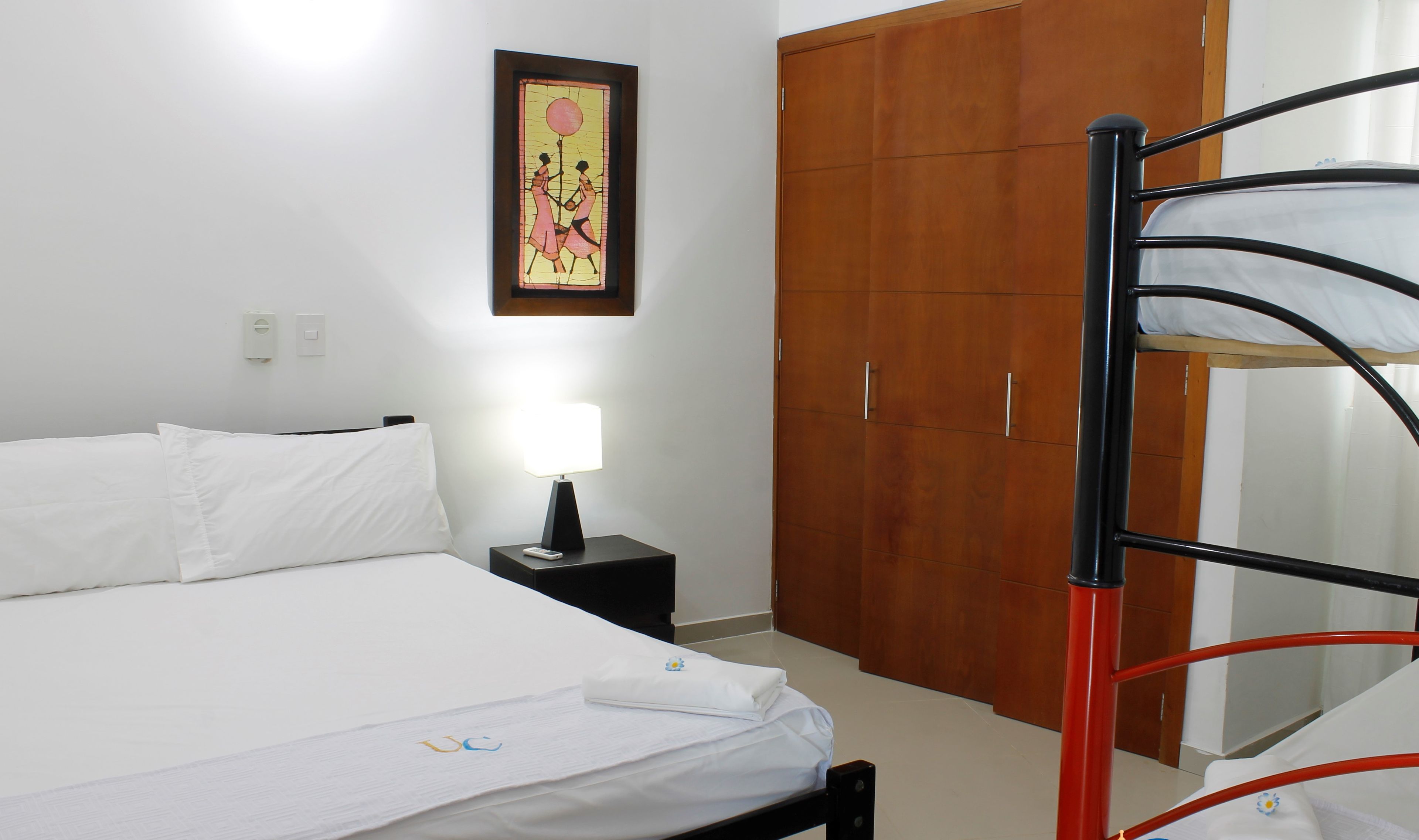 Ein Hotelzimmer mit Bett, Nachttisch, Lampe, Kleiderschrank und Etagenbett.
