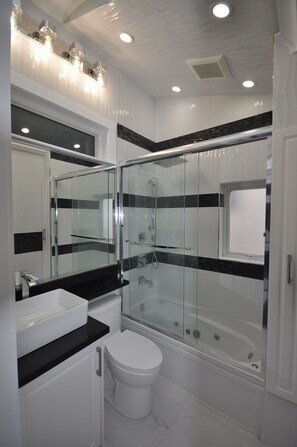 A modern bathroom with a glass-enclosed shower, a white toilet, and a large mirror above the sink. - Sunset Views (Vancouver)