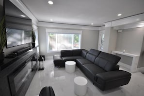 A modern living room with a sectional sofa, a flat-screen TV, and a minimalist design. - Sunset Views (Vancouver)