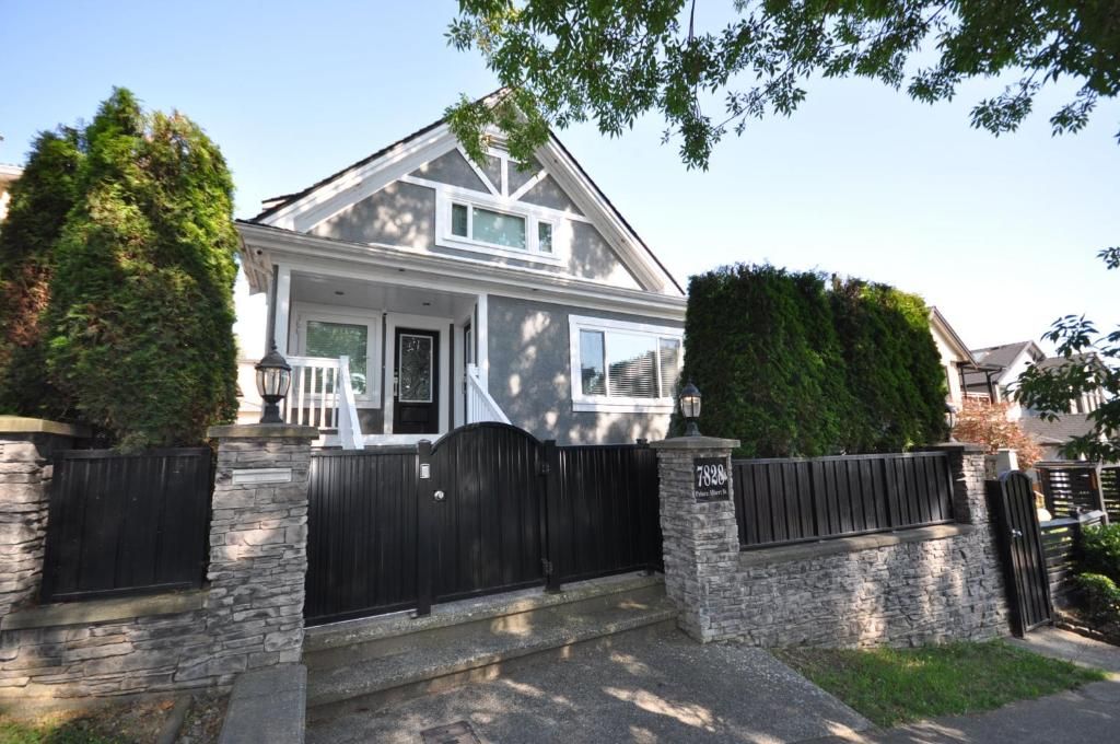 A two-story house with a stone facade, a black gate, and a well-maintained lawn.