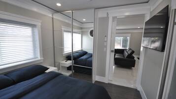 A modern bedroom with a large bed, a bedside table, a mirror, and a wardrobe.