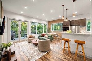 Une cuisine moderne avec des meubles en bois, un réfrigérateur en acier inoxydable et un coin repas comprenant une table et des chaises.