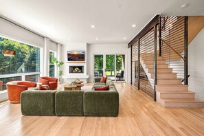 Uma sala de estar espaçosa com um sofá grande verde, uma lareira e uma escada com degraus de madeira.