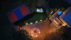 Vista aérea de uma propriedade com piscina, hidromassagem e área de estar circular ao ar livre.