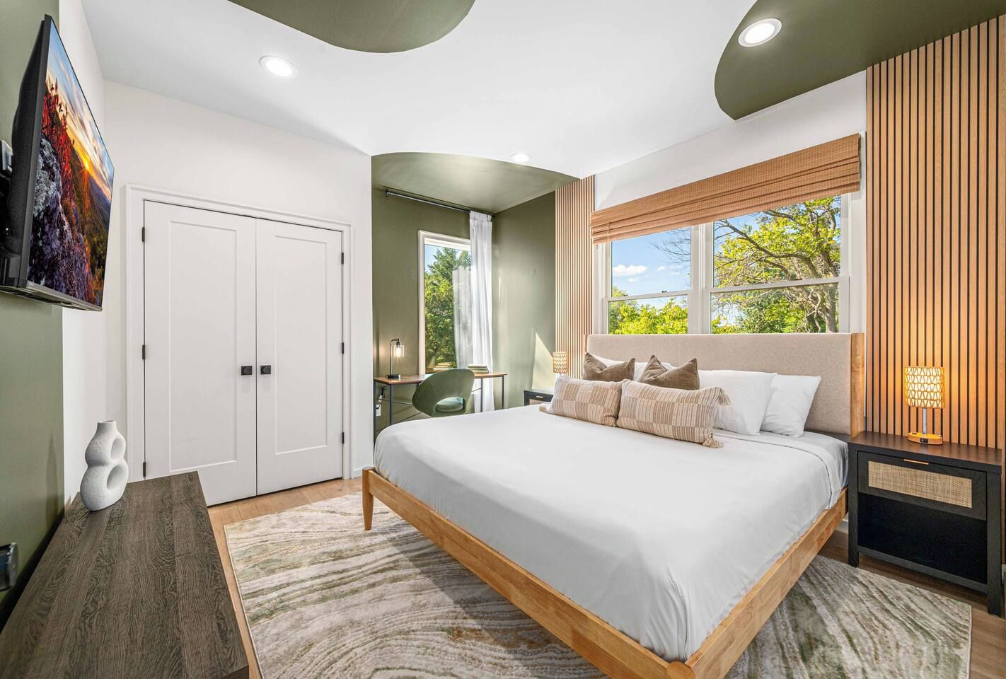A bedroom with a bed, a desk, a chair, a window, and a door.