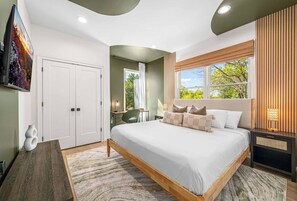 A bedroom with a bed, a desk, a chair, a window, and a door. - Sleeps 26 | Pickleball+Game Room+Theater+Sauna (Leicester)