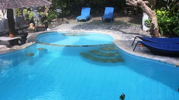 A swimming pool with lounge chairs and a stone pathway.
