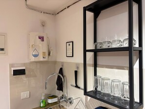 Eine Küche mit Wasserspender, Spüle und einer Glaswaren-Abteilung.