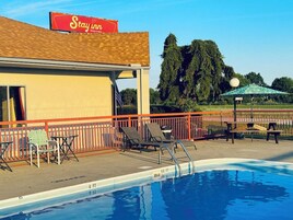 Un área de piscina con sillones de descanso y un cartel que dice Stay Inn.