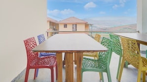 Un balcón con mesa y sillas, con vistas a una zona residencial con casas y cielo despejado.