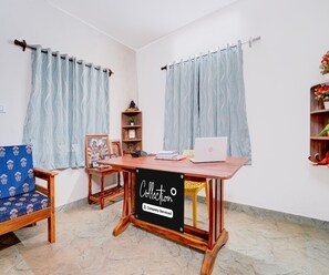 A room with a wooden desk, a chair, a laptop, and a shelf with decorative items.