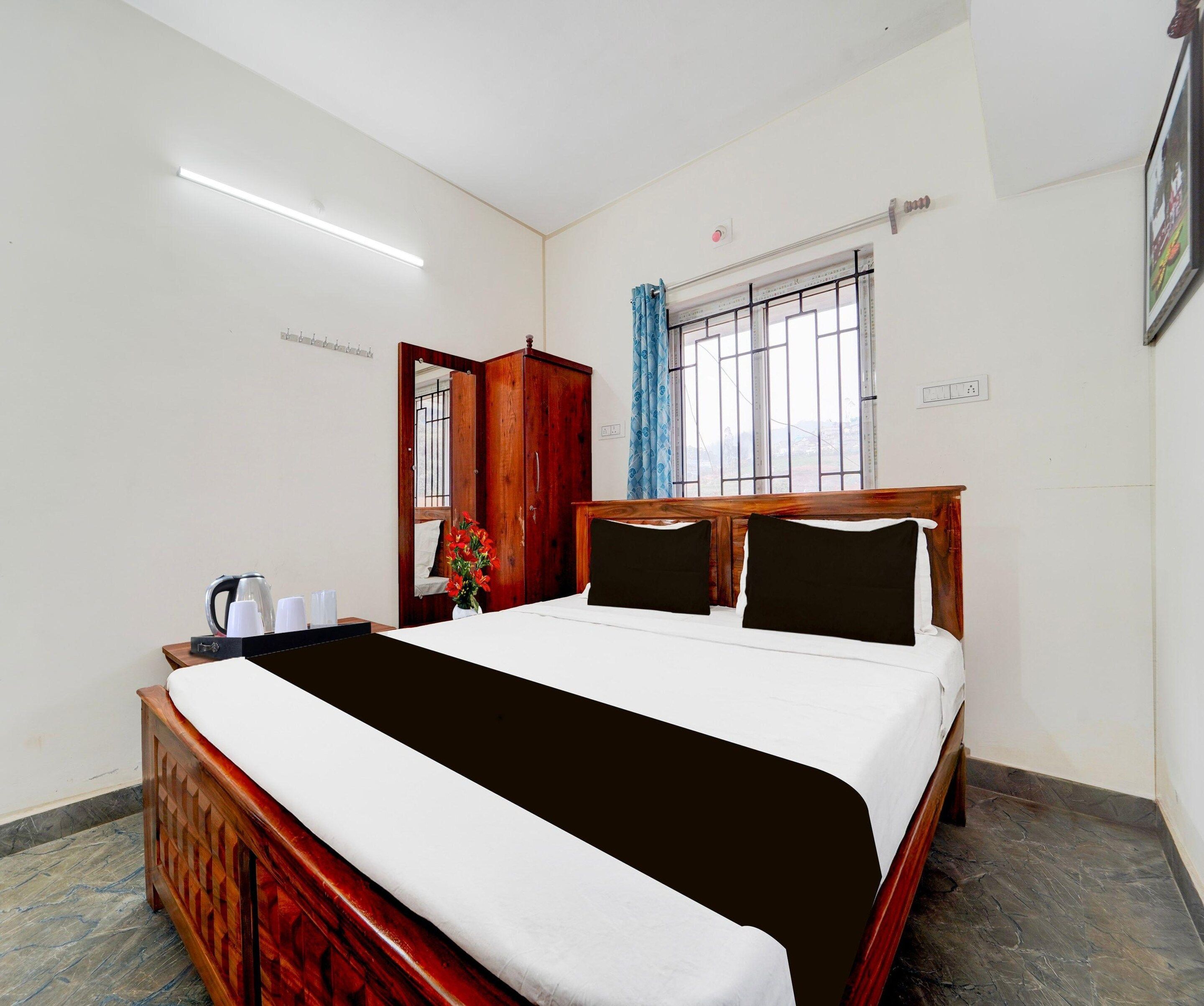 Ein Hotelzimmer mit einem Bett, einem Nachttisch mit Wasserkocher, einem Fenster mit Gitter und einem Vorhang.