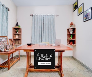 A room with a wooden table, a laptop, a bookshelf, and a curtain.