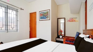 Habitación de hotel con cama, puerta de madera, un cuadro, espejo, silla y ventana con barrotes.