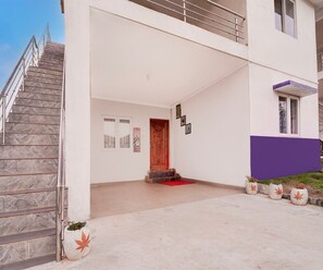 A modern building entrance with a staircase, a wooden door, and a red mat.