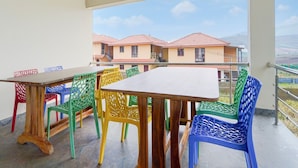 Un balcón con una mesa y sillas coloridas, con vistas a una hilera de casas.