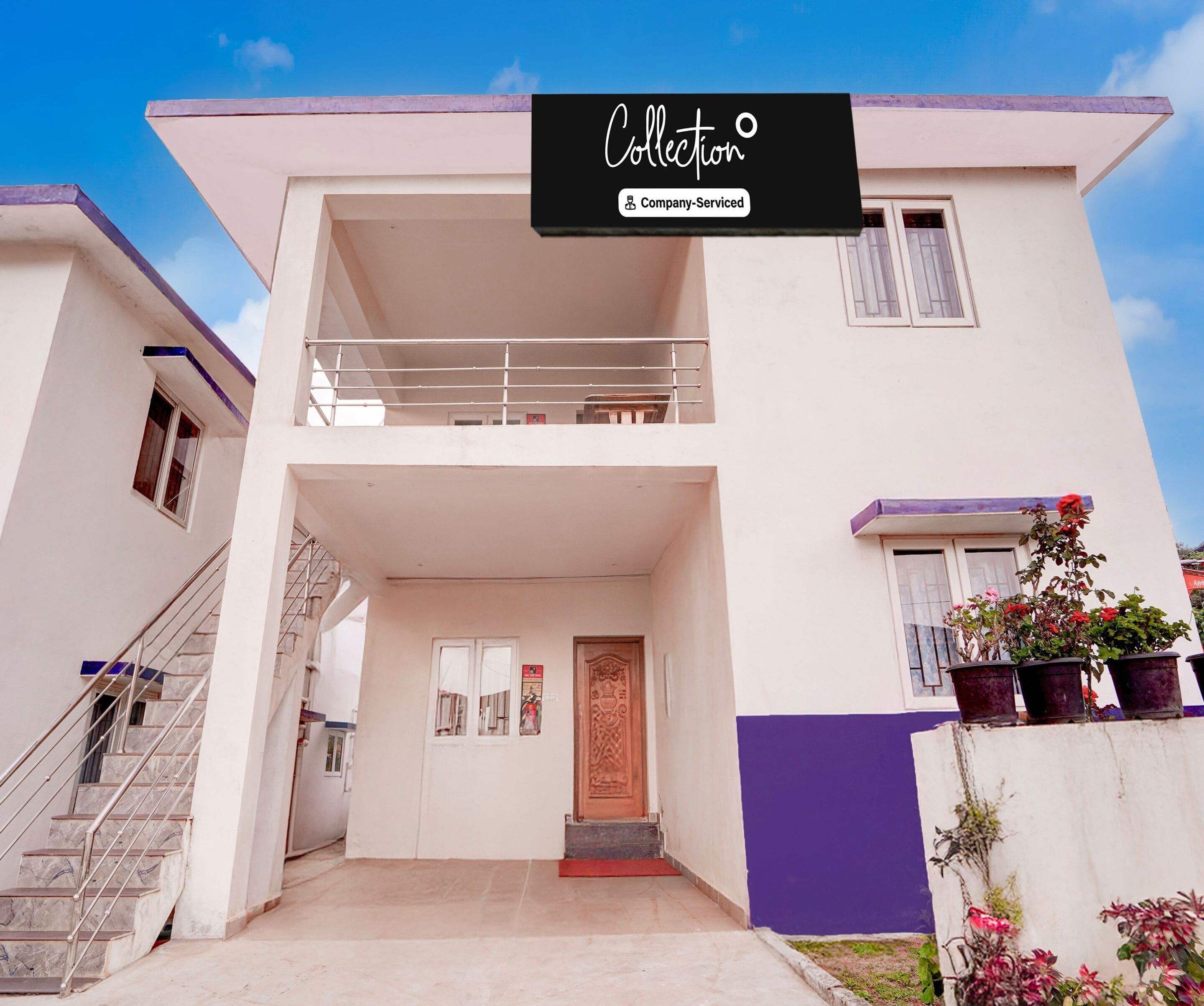 A two-story building with a balcony, a staircase, and a door with a decorative panel.