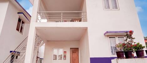 A two-story building with a balcony, a staircase, and a door with a decorative panel.