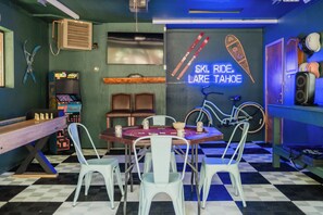 Ein Zimmer mit kariertem Boden, einer Neonreklame mit der Aufschrift 'SKI. RIDE. LAKE Tahoe', einem Tisch mit Stühlen und einer Jukebox.