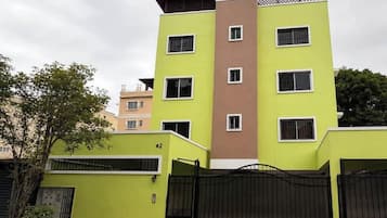 Edificio residencial de varios pisos con techo plano, entrada protegida por una reja y un cartel con el número de la unidad.