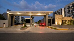 Una entrada con reja a un complejo residencial de estilo arquitectónico moderno, con un corredor cubierto y un letrero llamativo.