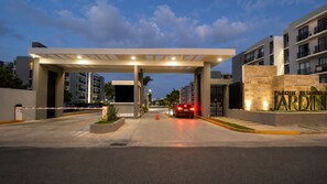 Una entrada con reja a un complejo residencial de estilo arquitectónico moderno, con un corredor cubierto y un letrero llamativo.