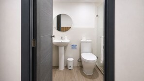 Un baño con lavamanos, inodoro y espejo blancos.