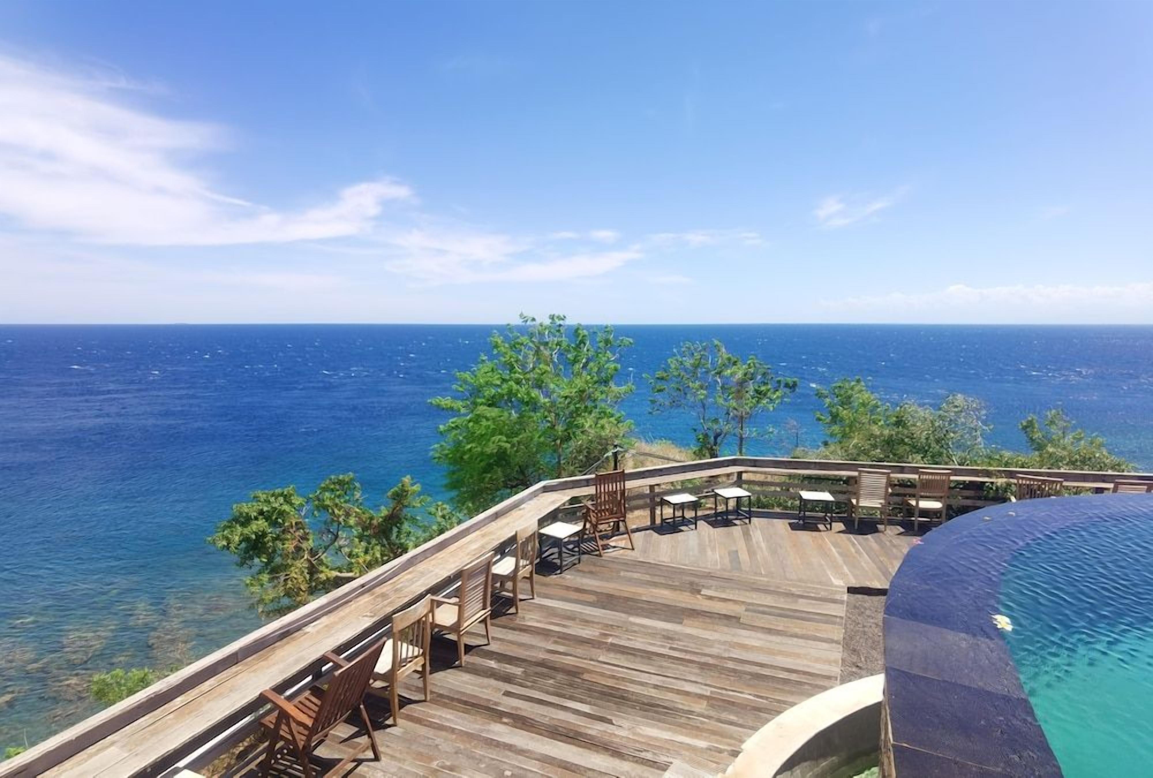 A wooden deck with outdoor seating overlooking a body of water.