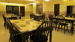 Sala de conferência com várias mesas e cadeiras, equipada com ventiladores de teto e iluminação embutida.