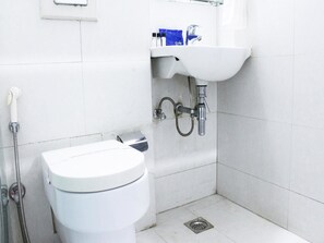A small, clean bathroom with a white toilet, a sink, and a shower. - OYO Premium Ambience Mall 2 (Gurugram)