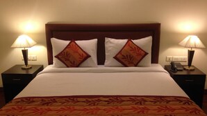 Quarto de hotel com uma cama grande, duas mesas de cabeceira e duas luminárias.