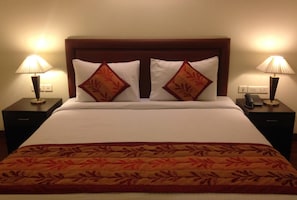 A hotel room with a large bed, two bedside tables, and two lamps. - OYO Premium Ambience Mall 2 (Gurugram)