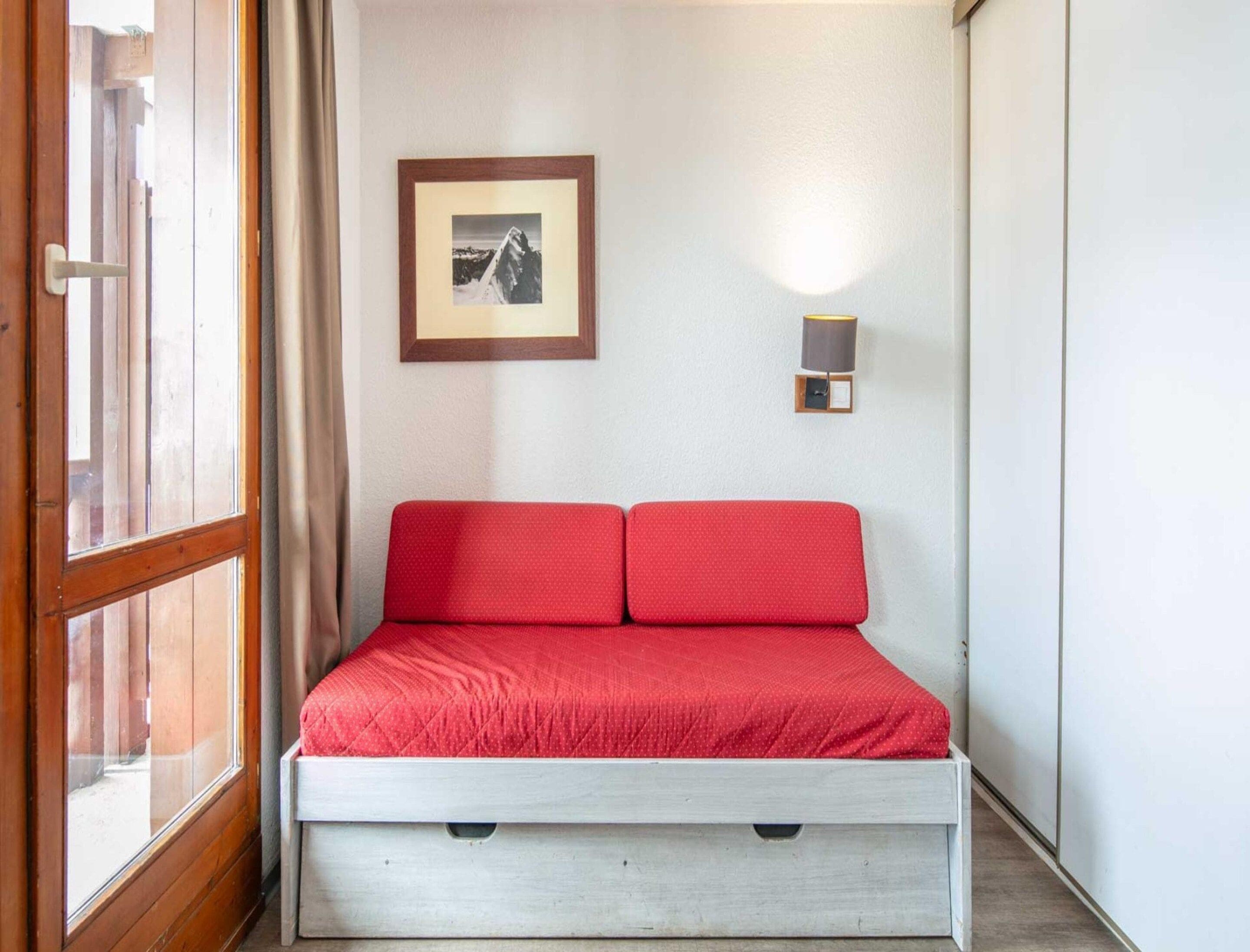 Ein gemütlicher Raum mit einem Bett, einem gerahmten Bild an der Wand und einer Wandleuchte.