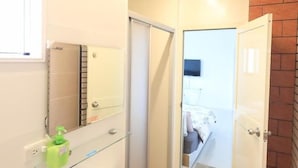 A bathroom with a white sink, a mirror, and a glass shelf. - Nice B&B (Luodong)